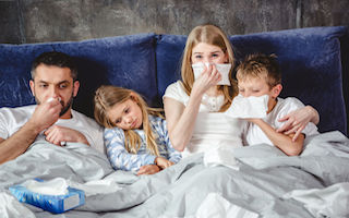 70543509 - family of four has a flue and lying on bed together